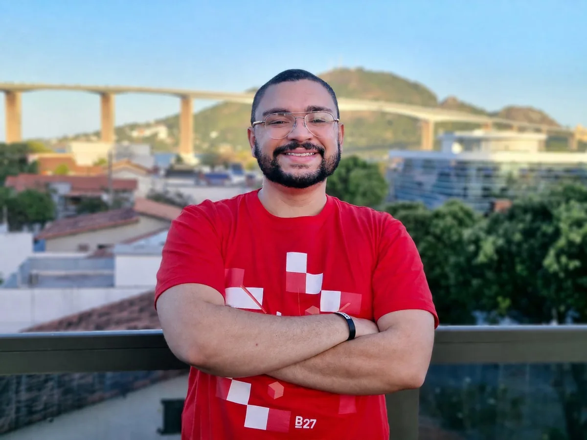 Tadeu Augusto, fundador da MakeFounder, de braços cruzados numa varanda com a cidade ao fundo